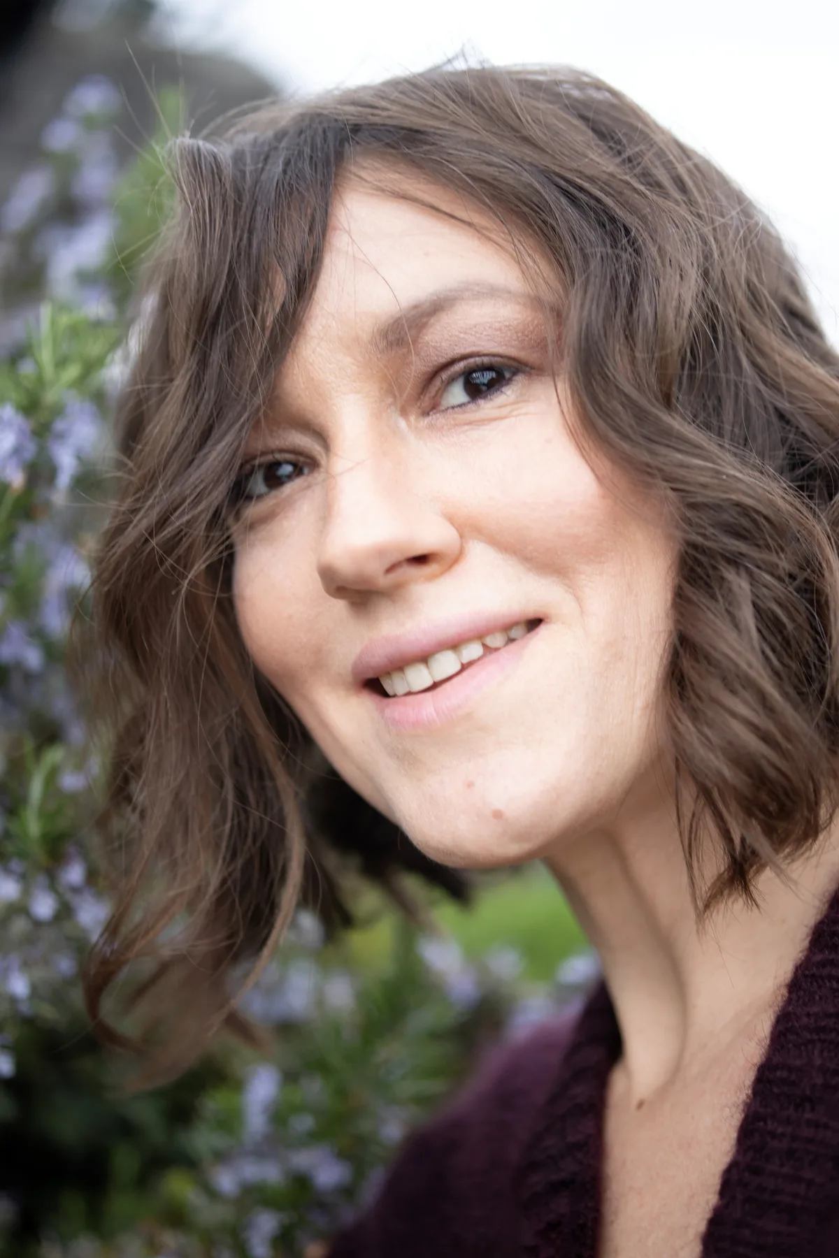 Eugenia Mashchenko: «Nationalitäten und Grenzen haben für mich keine Bedeutung. Wichtig sind die menschlichen Werte.» Porträtfoto einer Frau mit braunen, schulterlangen Haaren vor einem Gebüsch.